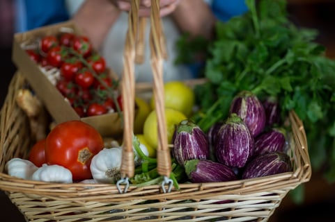 Close-up of female staff holding basket of vegetables in organic section of supermarket